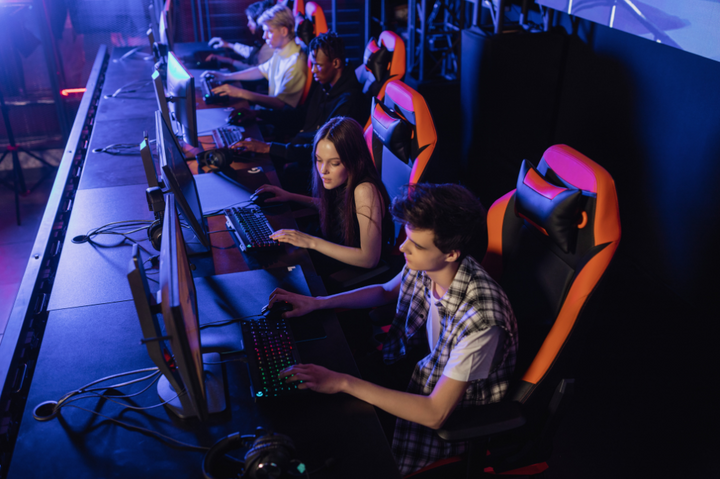 In a gaming room, young individuals are immersed in video games, seated on the best gaming chairs.