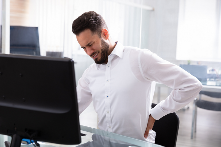 A man seated at a desk, contemplating when to replace his office chair for better comfort.